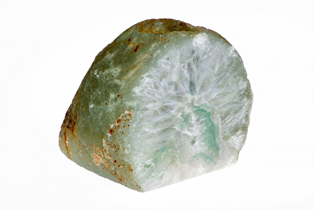 A polished stone specimen with a pale green outer layer, brown spots, and a white crystalline interior on a white background.