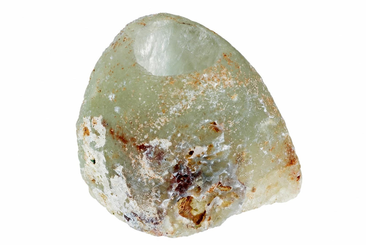 A pale green, rough stone with a hollowed top and brownish-white surface spots on a white background.