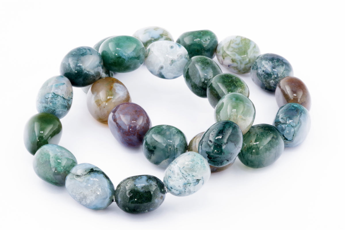 Close-up of polished natural gemstones in varying shades of green, brown, and white, arranged to form a Moss agate bracelet – Gem with smooth rounded beads.