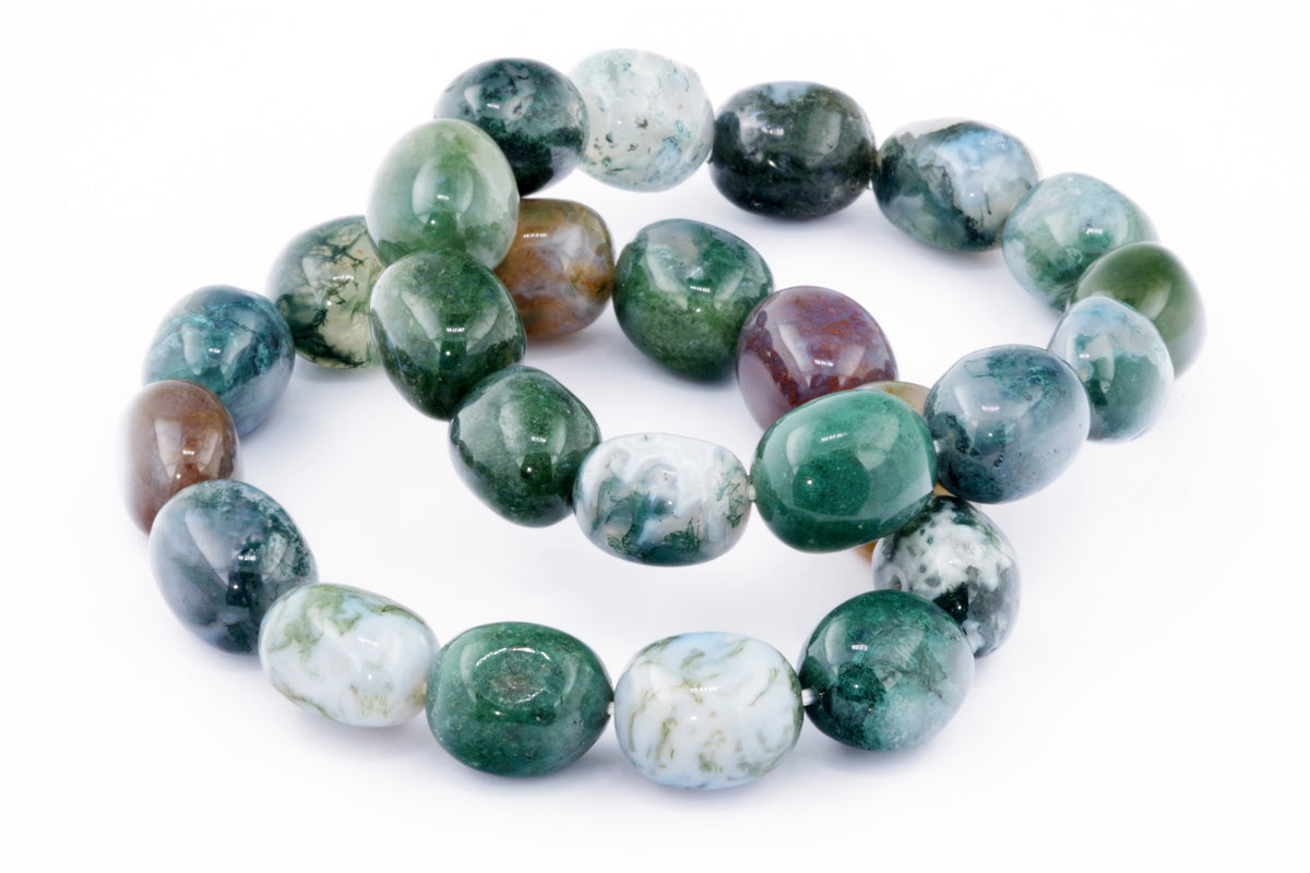 Close-up of polished natural gemstones in shades of green, white, and brown arranged as a Moss agate bracelet – Gem showcasing unique mineral patterns and crystal jewellery style.