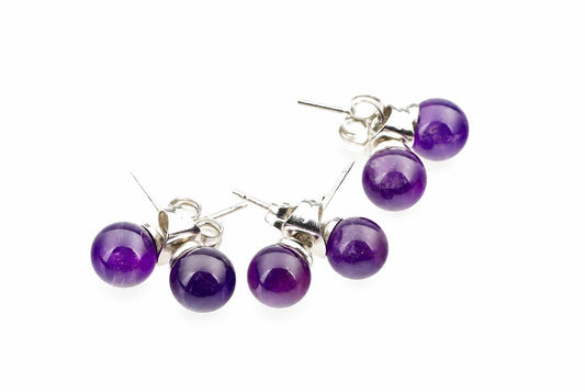 Four round purple amethyst stud earrings with silver-toned posts on a white surface.