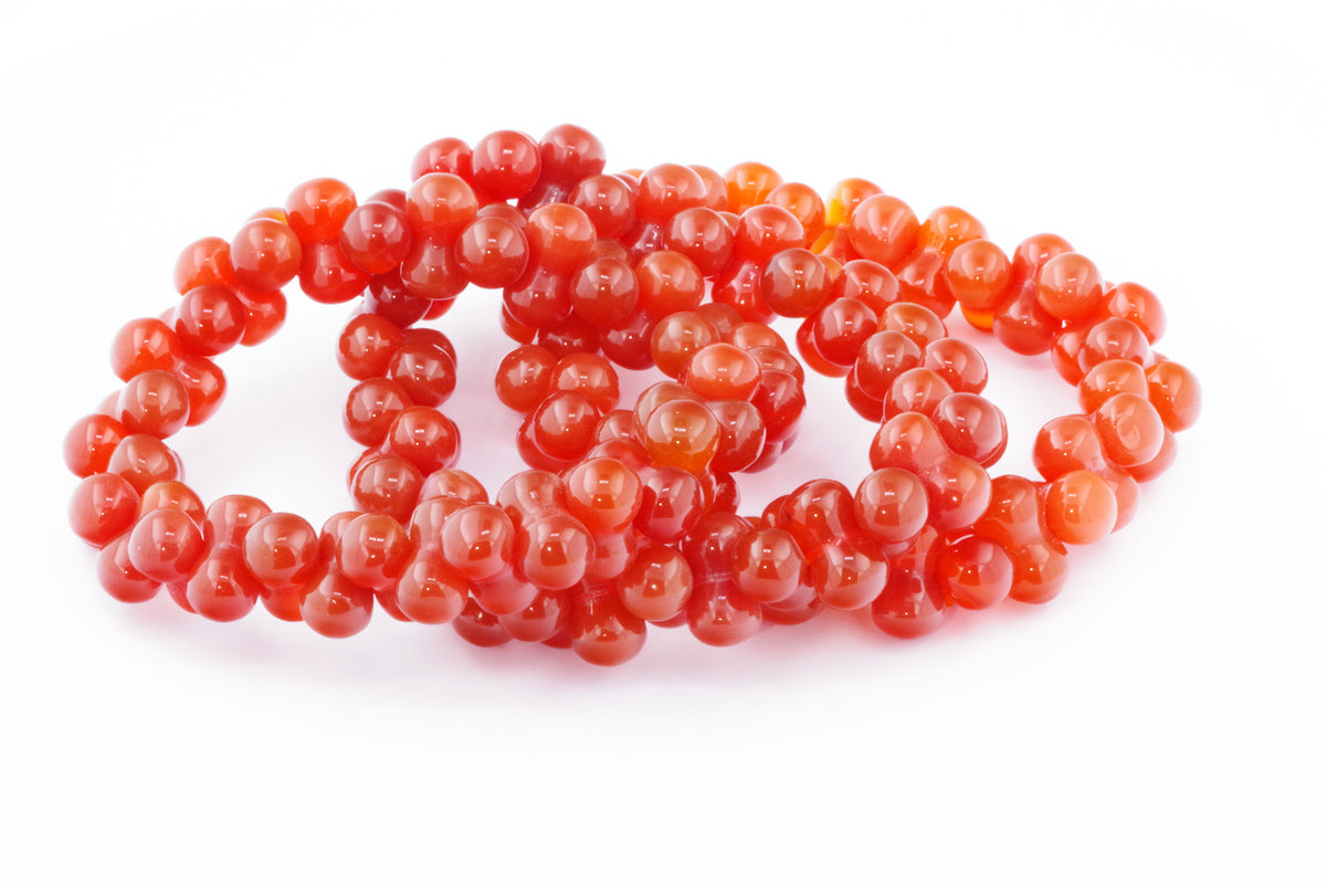 Three polished carnelian bead bracelets arranged closely together, showcasing vibrant orange-red natural crystals in the Carnelian bracelet – DNA style.