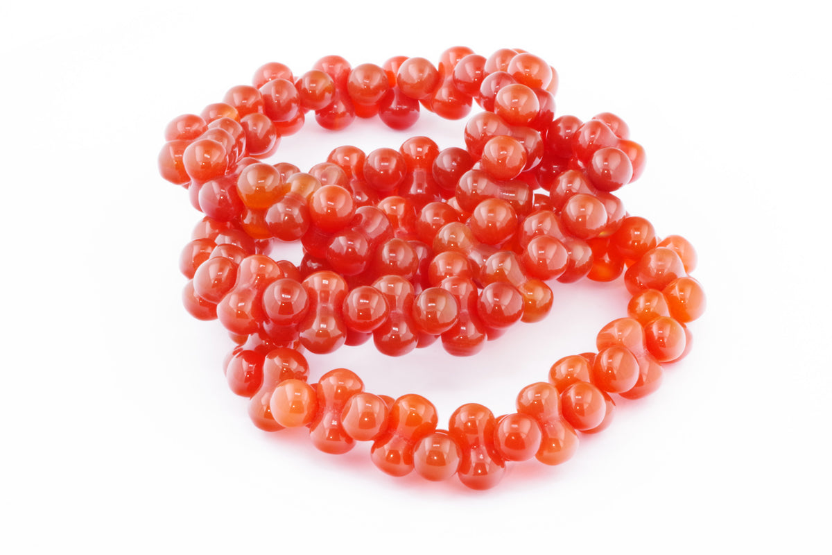 Carnelian bracelet – DNA featuring polished vibrant orange carnelian beads arranged in a unique connected pattern, showcasing natural crystal jewelry with a warm glow.