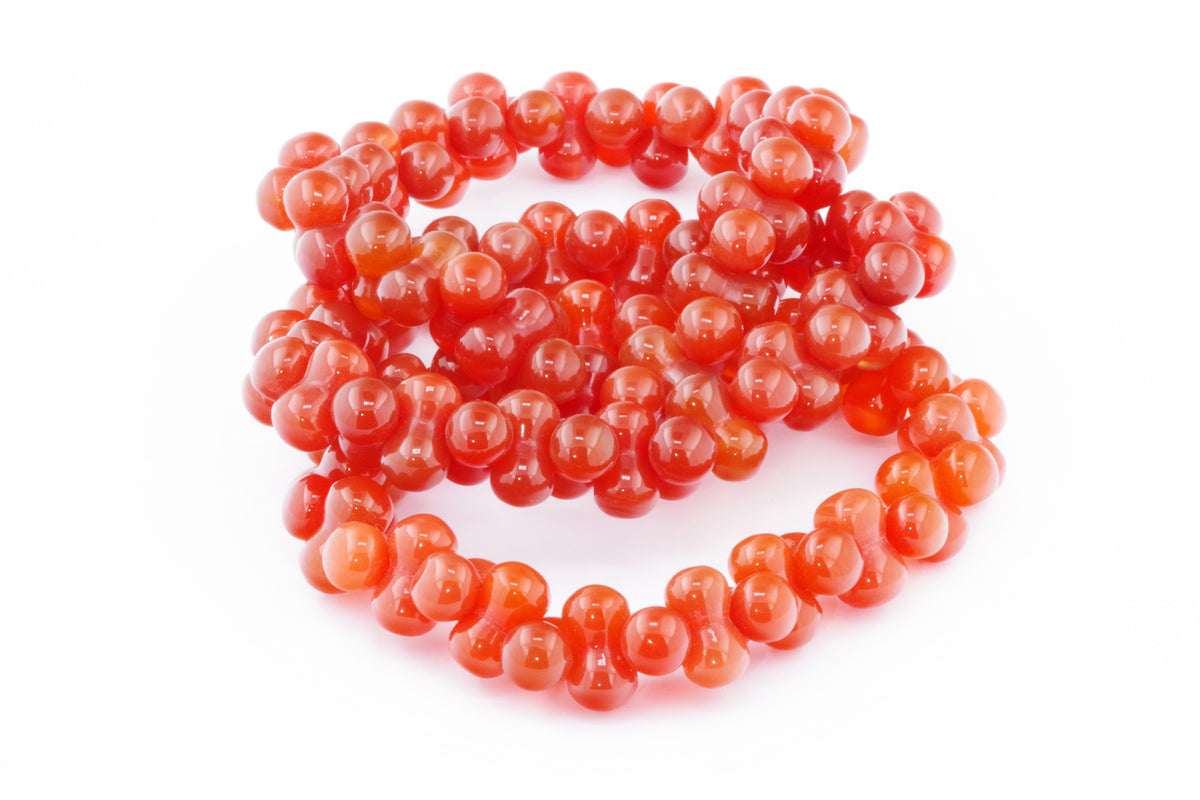 Close-up of a polished carnelian bracelet – DNA featuring deep orange-red natural crystal beads, arranged in a unique linked design suitable for crystal jewellery lovers.