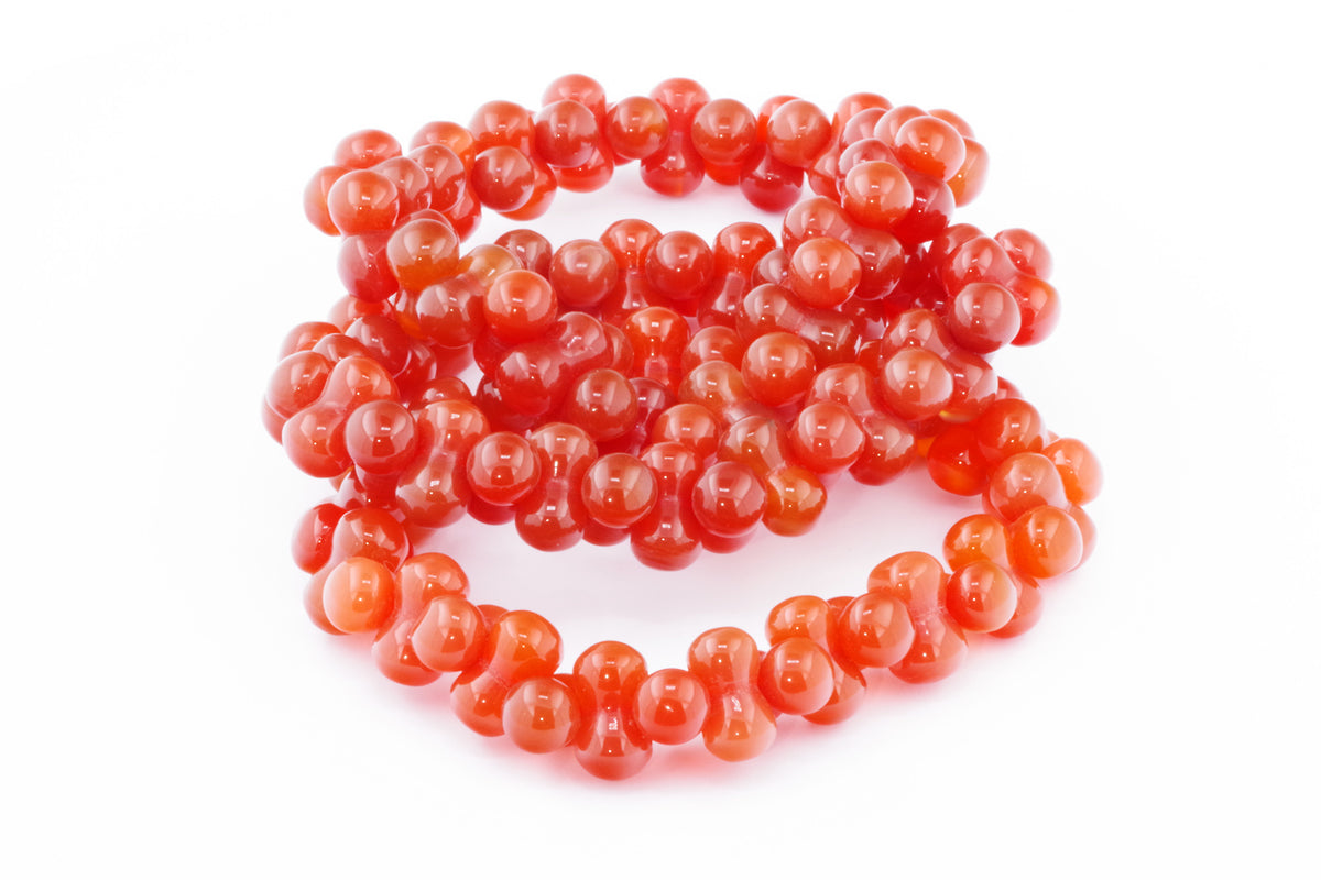 Carnelian bracelet – DNA featuring polished vibrant orange-red carnelian beads intricately shaped and strung to form a unique crystal bracelet design.