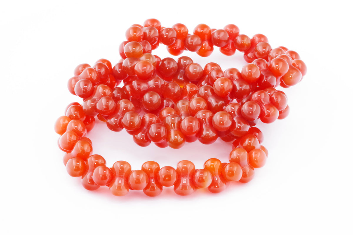Carnelian bracelet – DNA featuring polished natural carnelian crystal beads arranged in a unique, twisted design showcasing warm orange-red tones and smooth glossy finish.