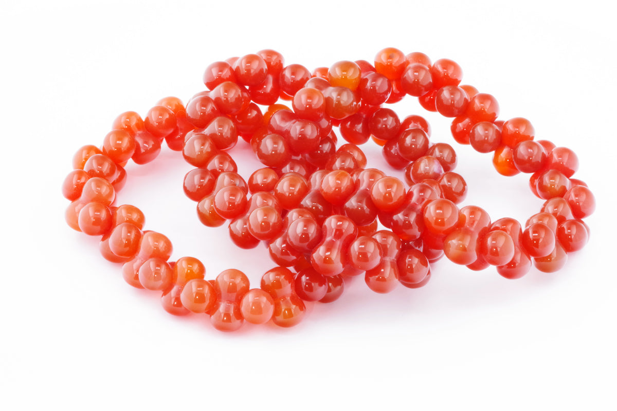 Carnelian bracelet – DNA featuring vibrant polished natural carnelian gemstone beads with a smooth, glossy finish showcasing rich red-orange hues in a stylish crystal bracelet.