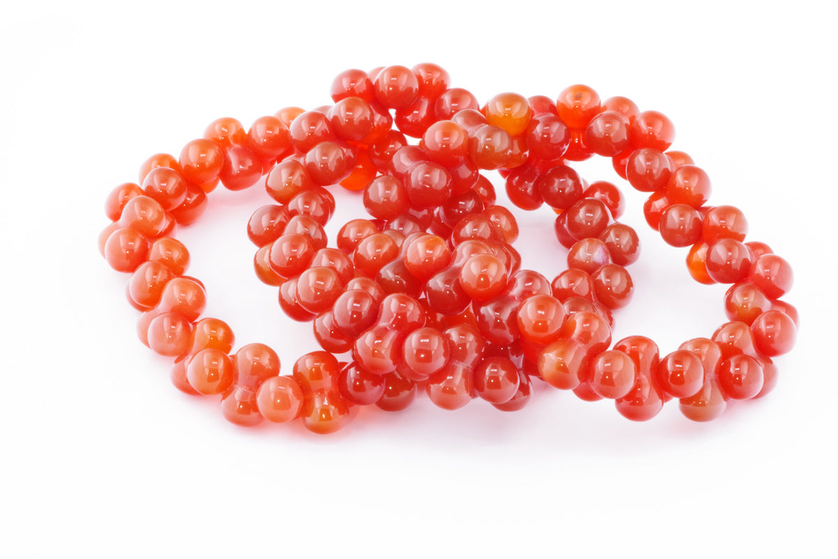 Three polished carnelian bracelets featuring rounded beads in varying shades of deep orange and red, styled to highlight the natural crystal's smooth, glossy finish, Carnelian bracelet – DNA.