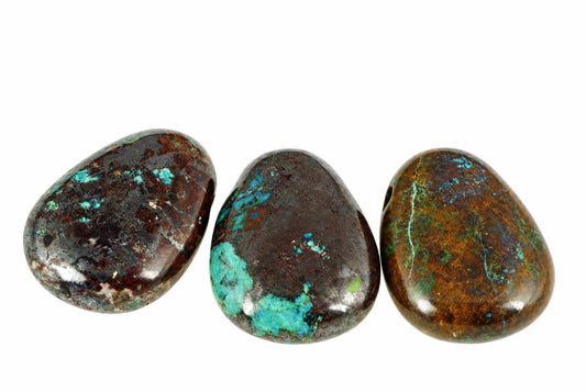 Polished teardrop chrysocolla pendants with blue and green patches across dark brown surfaces are arranged together against a white background.