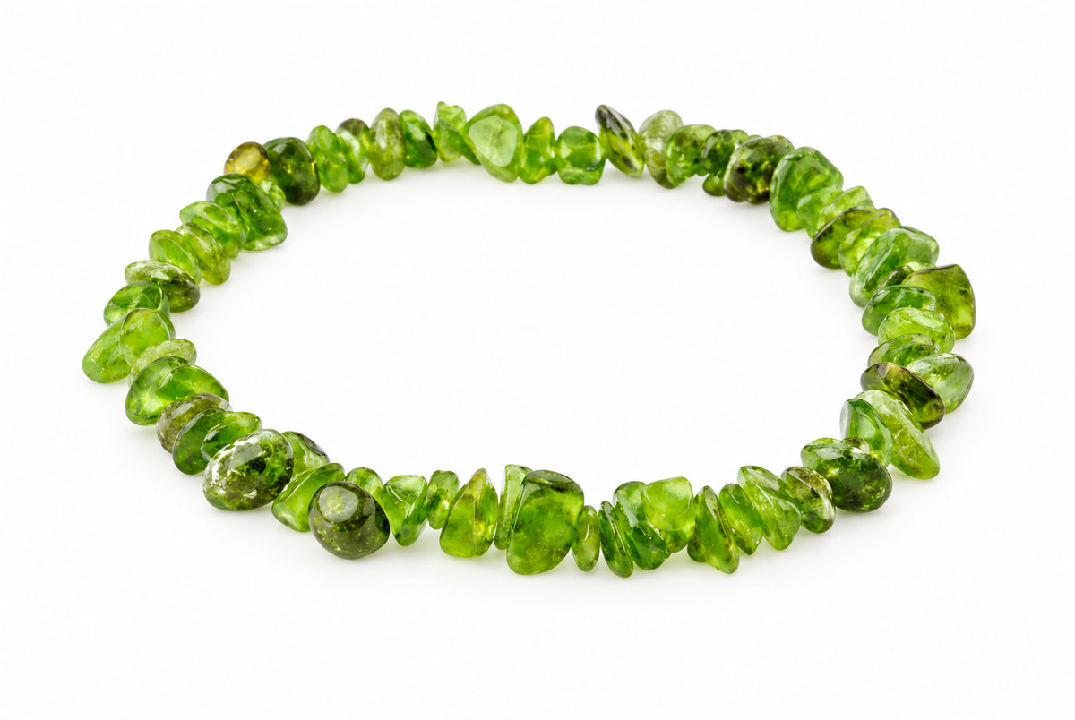 A bracelet made of irregular, polished green chips arranged in a circle on a white surface.