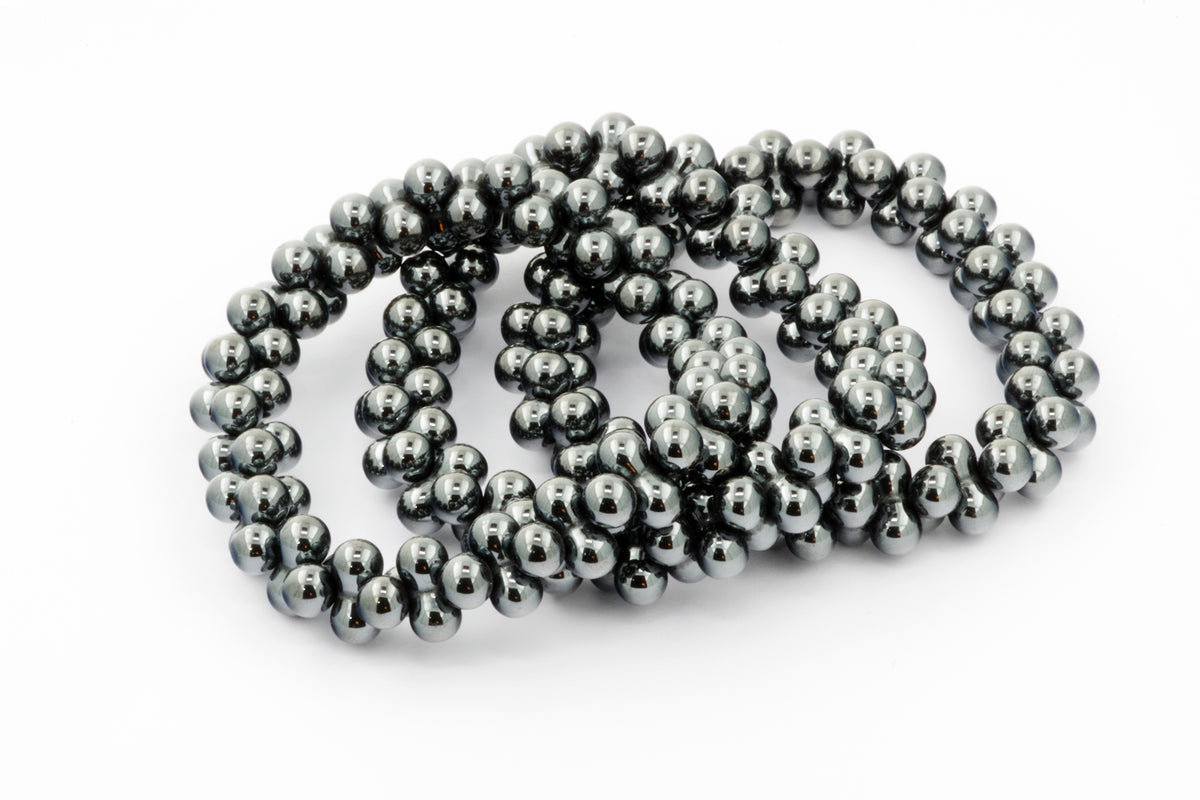 Three polished dark metallic crystal bead bracelets arranged on a white background, showcasing the Hematite bracelet – DNA with smooth, reflective beads known for grounding and healing properties.