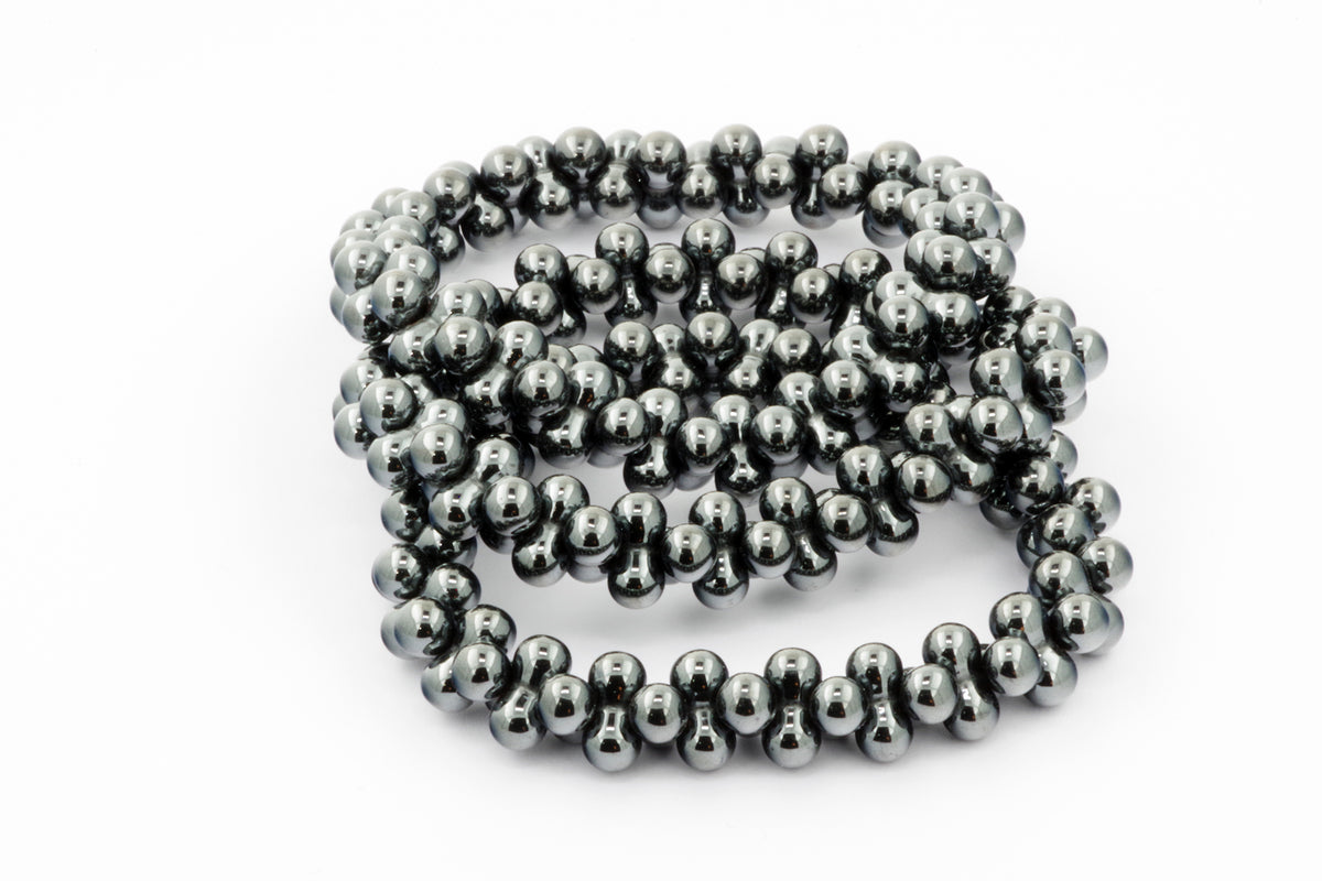 A close-up of a polished Hematite bracelet – DNA featuring smooth, reflective black hematite gemstone beads arranged in a continuous loop on a white background.
