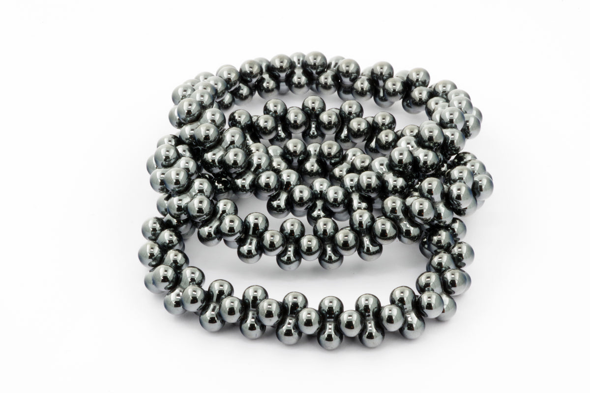 Close-up of a shimmering Hematite bracelet – DNA, featuring polished dark grey hematite beads arranged in a continuous loop, ideal as crystal jewellery for grounding and protection.