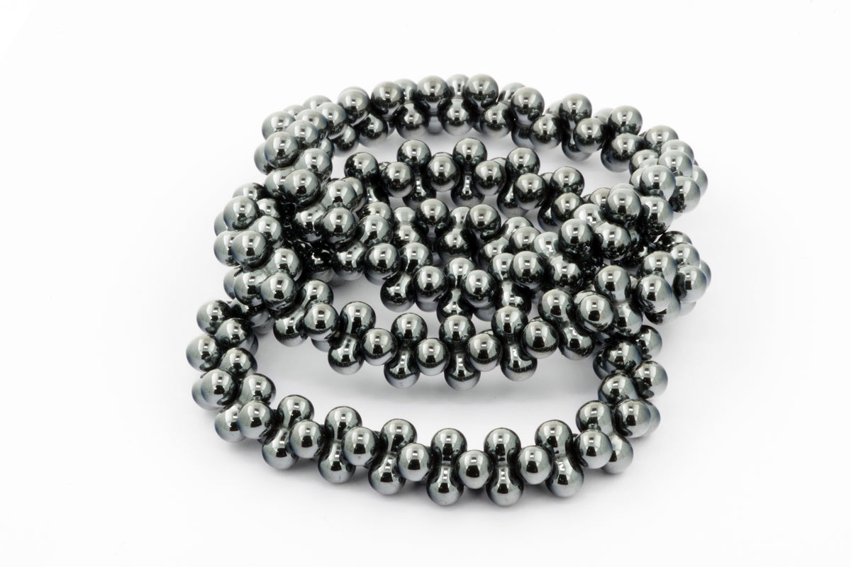 Close-up of a polished natural hematite bead necklace arranged in loops, showcasing the metallic dark gray smooth spheres of the Hematite bracelet – DNA, ideal for crystal jewellery and healing crystals collections.