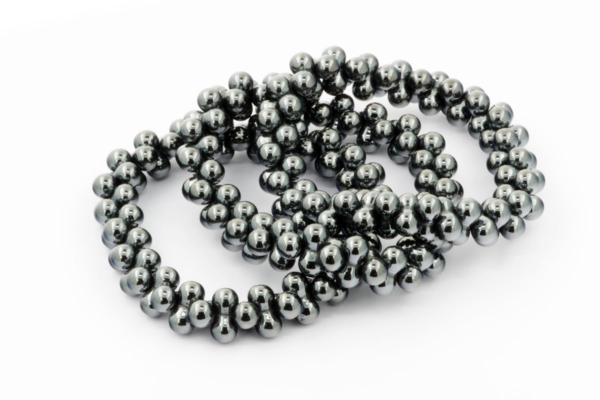 Hematite bracelet – DNA made of polished black hematite beads, reflecting light on a white background, showcasing natural crystal gemstone jewelry.