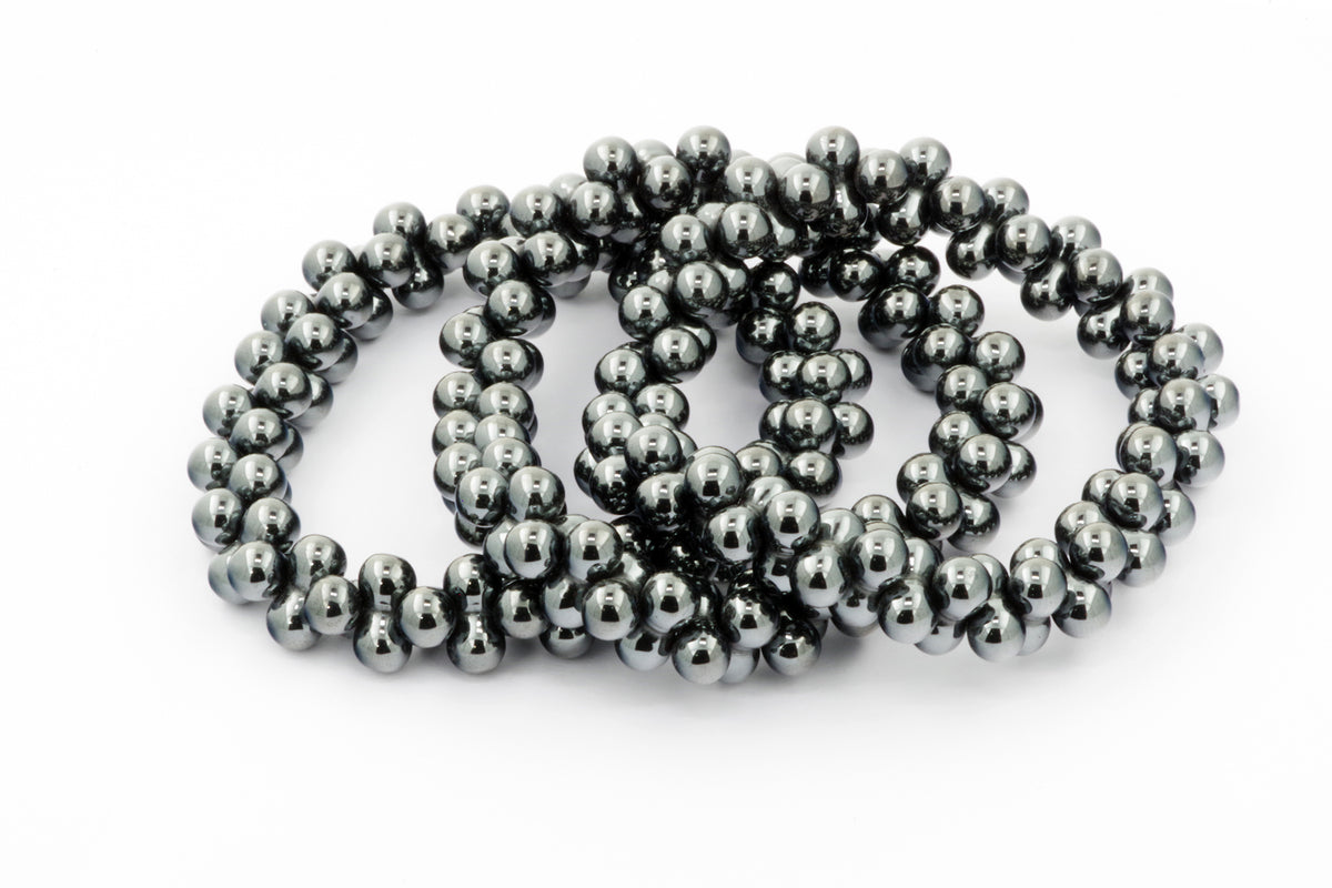 Three intertwined Hematite bracelet – DNA pieces made of polished dark metallic natural crystals arranged on a white background, showcasing their smooth spherical beads and reflective surface.
