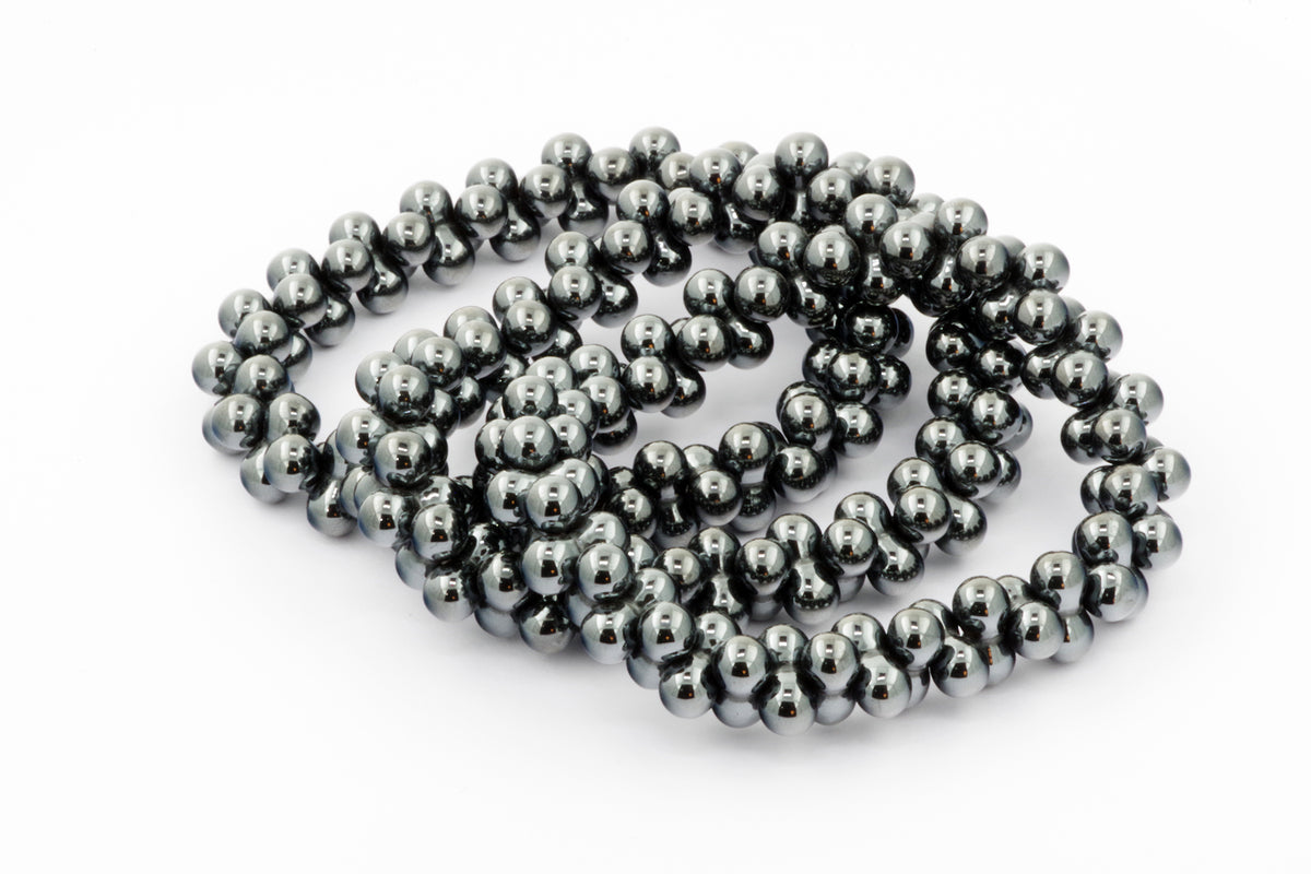 Close-up of a polished Hematite bracelet – DNA featuring smooth, reflective black metallic beads arranged in multiple strands on a white background.