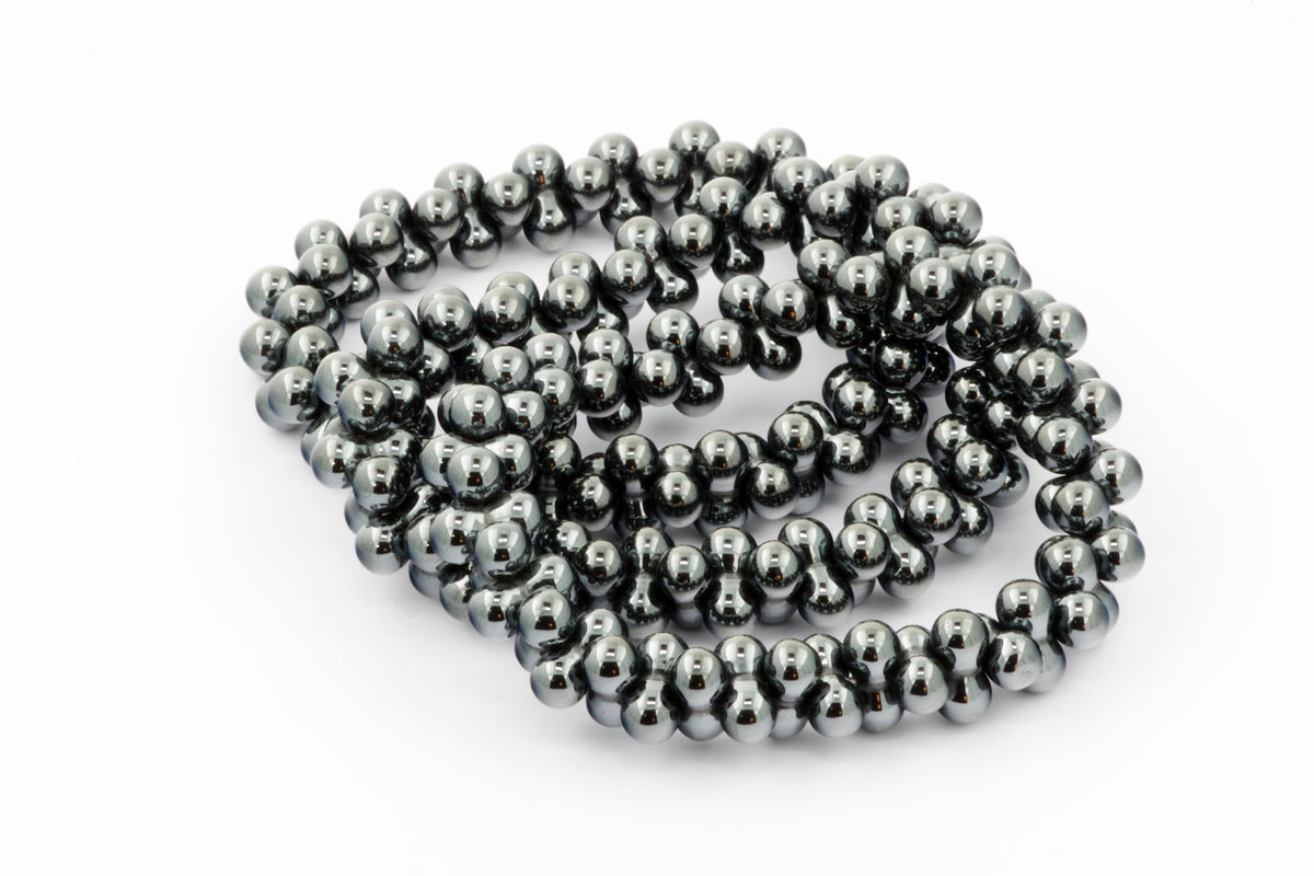 Close-up of a polished Hematite bracelet – DNA featuring smooth, shiny dark gray beads arranged in a continuous loop, highlighting mineral gemstone jewelry for grounding and healing.