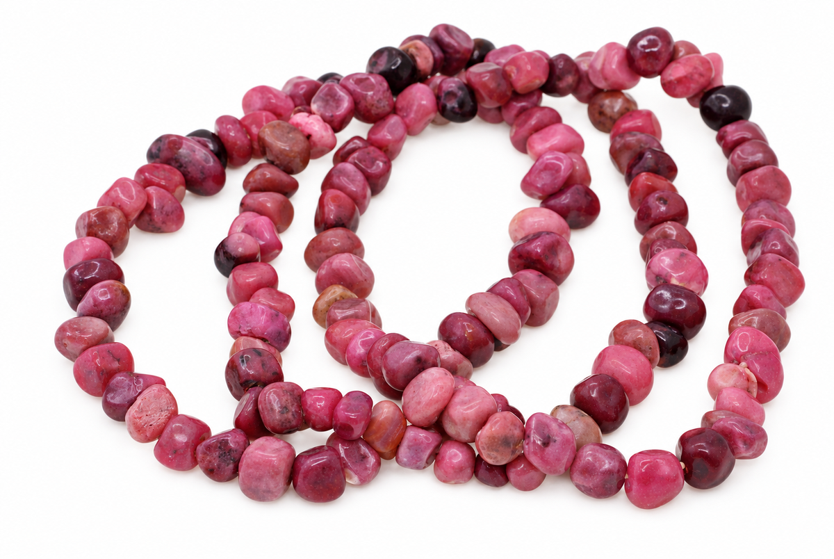 A necklace of polished rhodonite chips in shades of pink, red and dark purple arranged on a white surface.