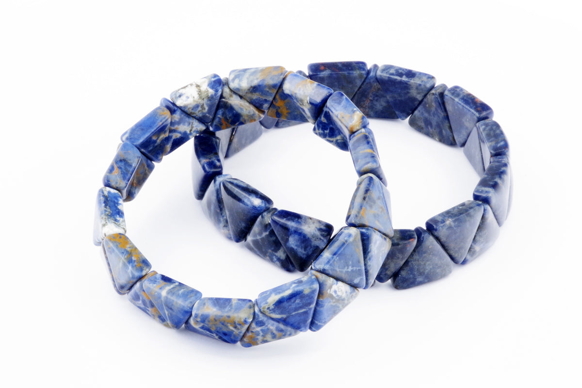 Two Sodalite bracelet – Triangle pieces made of polished blue and white natural crystal gemstones, arranged on a white background to highlight their geometric shapes and vibrant colors.