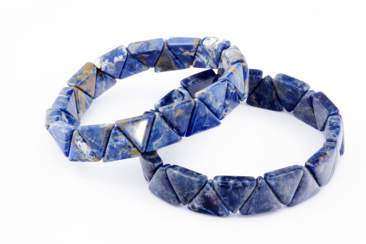 Two polished Sodalite bracelet – Triangle pieces featuring deep blue and white marbled triangular gemstones arranged on elastic bands against a white background.