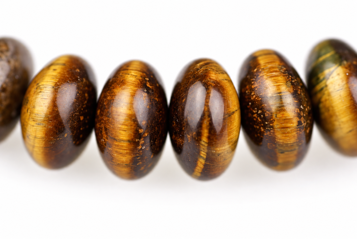 A row of polished, oval beads with golden and dark brown stripes on a white surface.