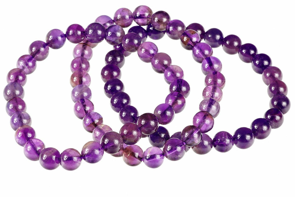 A coiled strand of round, polished purple beads on a white background.