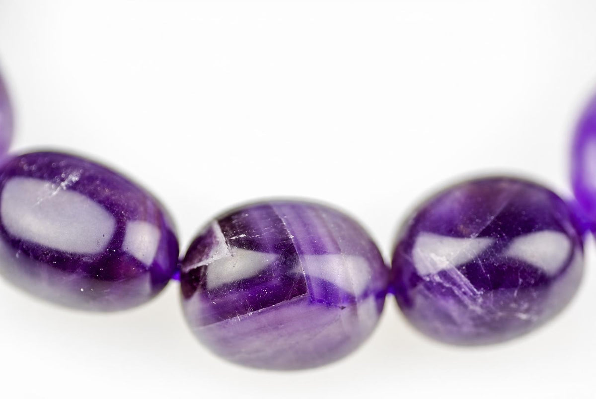 Three polished purple beads with white inclusions on a pale surface.