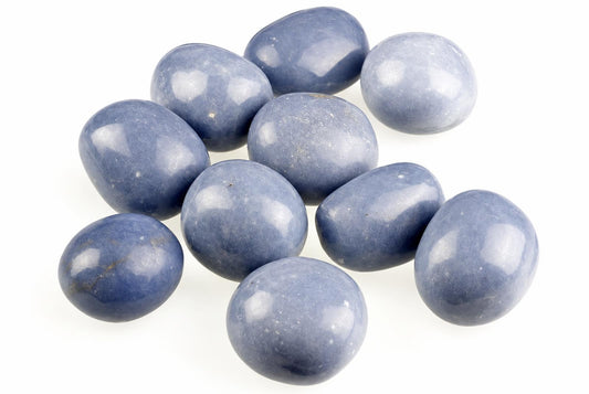 A group of smooth, polished blue stones with white speckles arranged on a pale surface.
