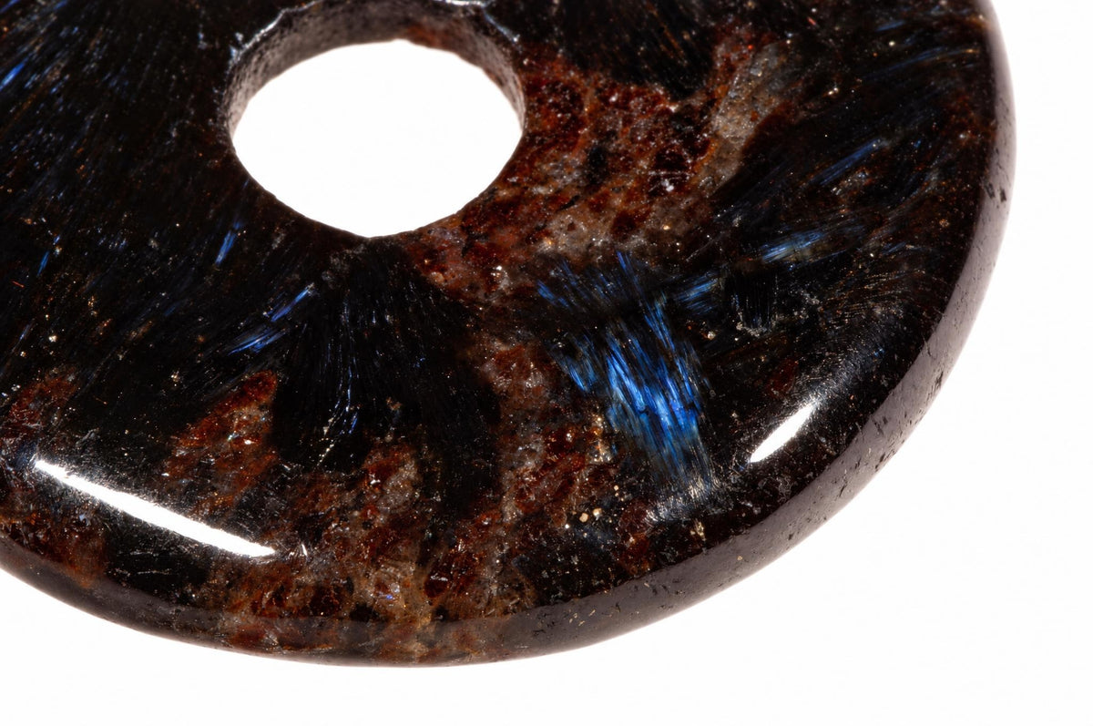 A polished, dark brown donut-shaped pendant with a central hole and visible blue iridescent streaks on a white background.