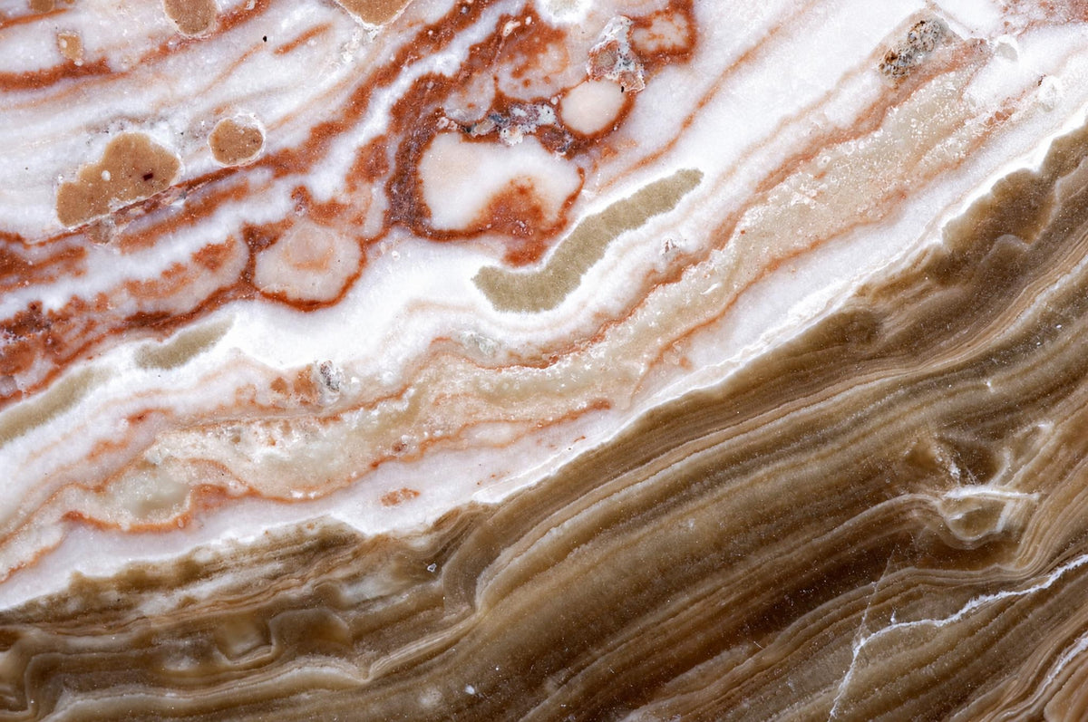 A polished stone slab with swirling white, brown, and reddish-brown bands on a dark surface.
