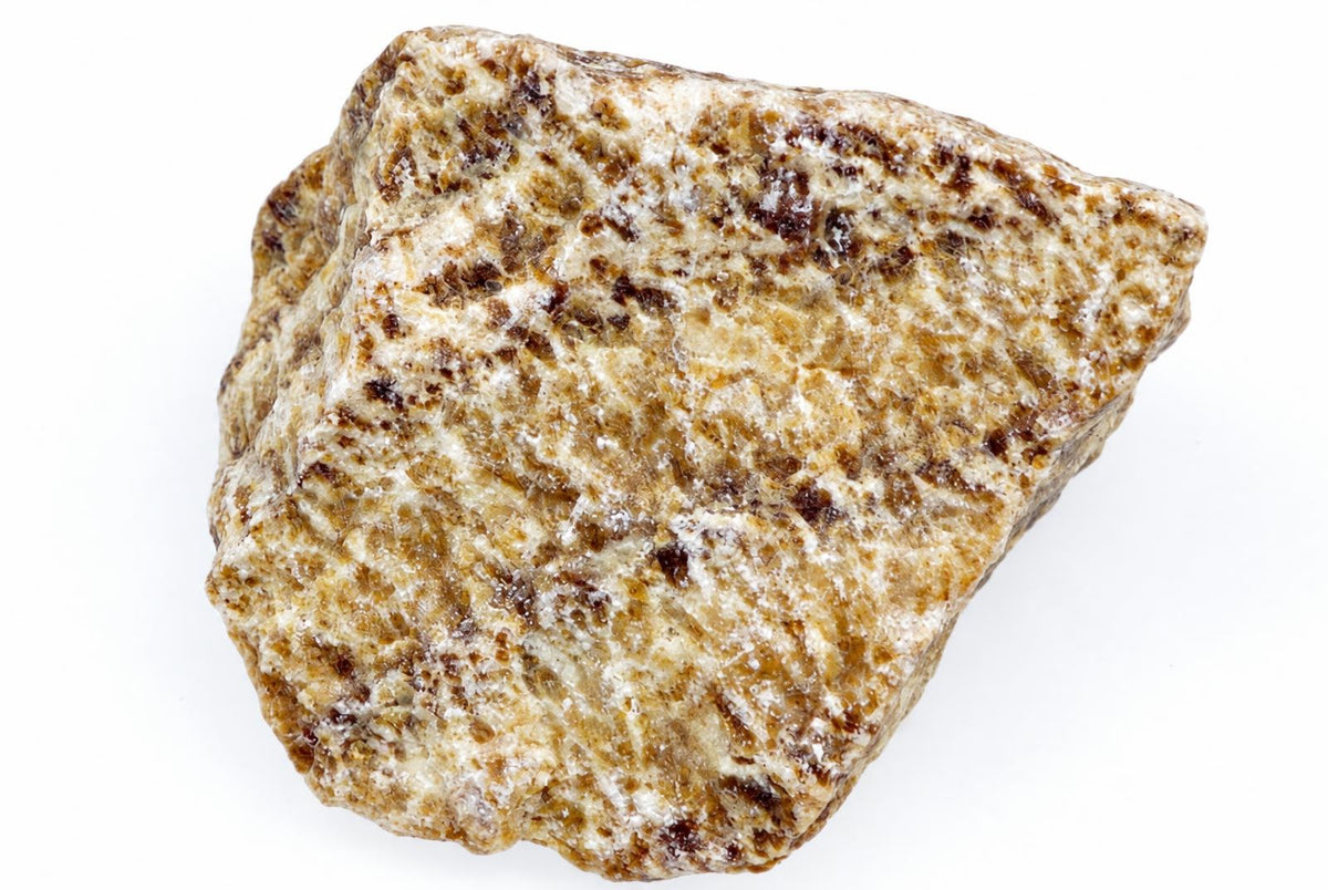 A raw aragonite specimen with a rough, irregular shape and a speckled surface of white, tan, and dark brown minerals on a plain background.