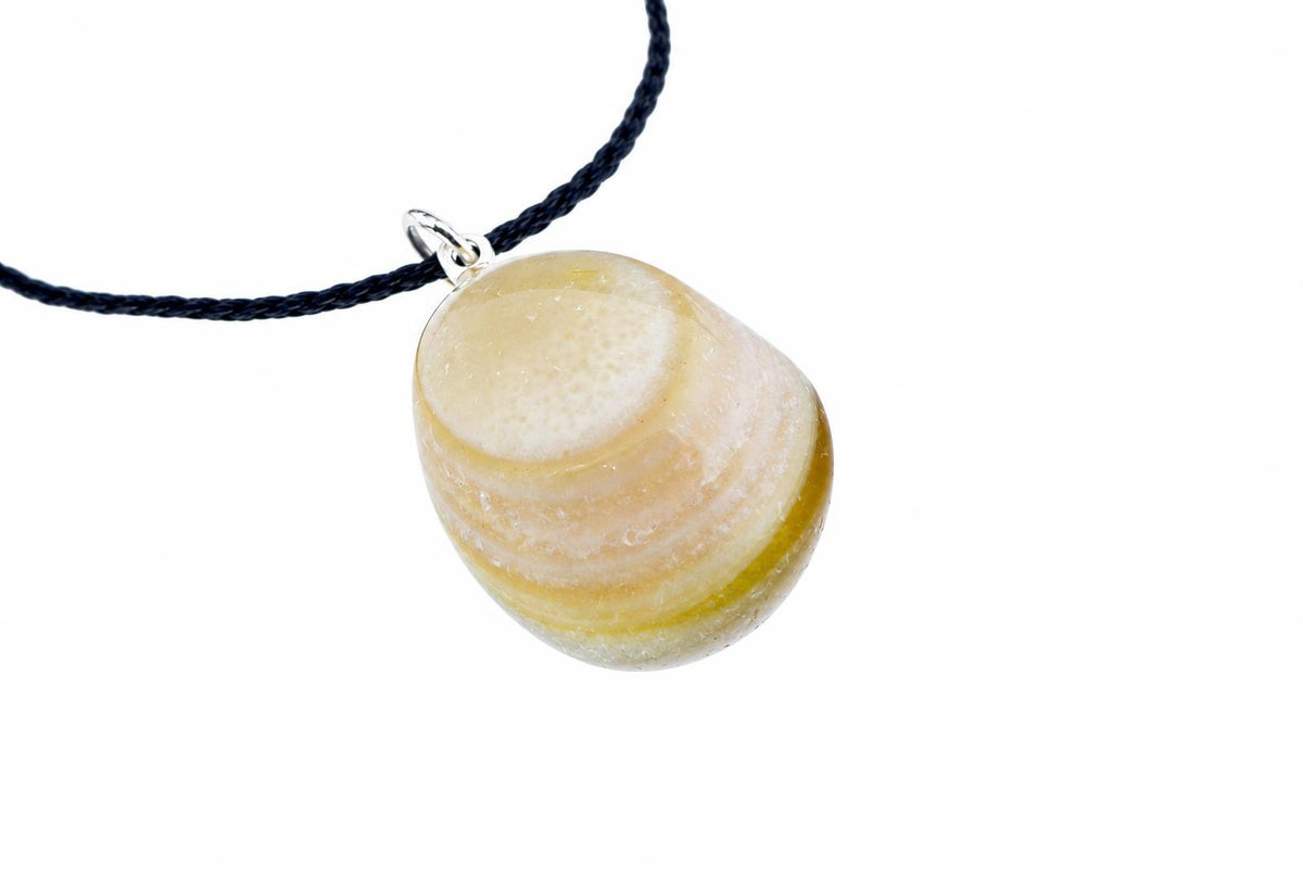 A smooth banded agate pebble pendant shows curved cream, pale yellow and white bands, hanging from a black cord on white.