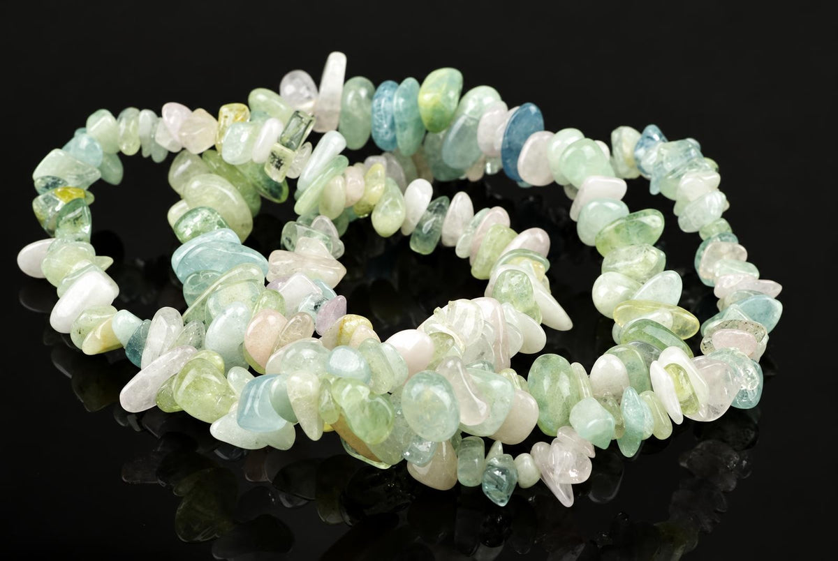 A beryl chip bracelet with pale green, blue, white and yellow stones on a dark reflective surface.