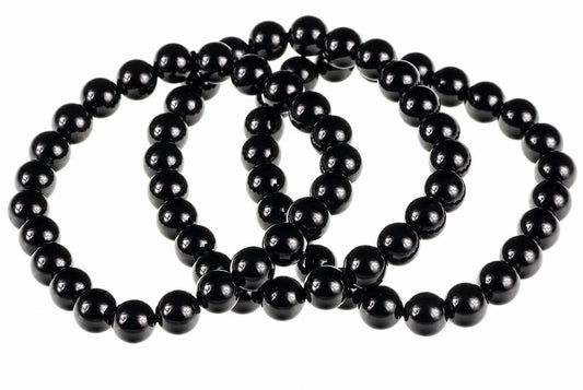 A black onyx bracelet with round beads arranged in a loop on a white surface.