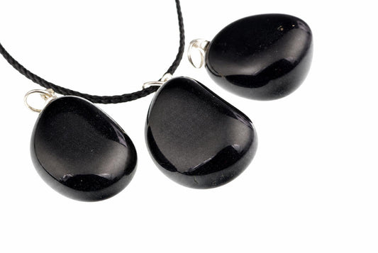 Three smooth black onyx pendants have rounded pebble shapes and reflective surfaces, with silver-colored loops and a black cord on white.