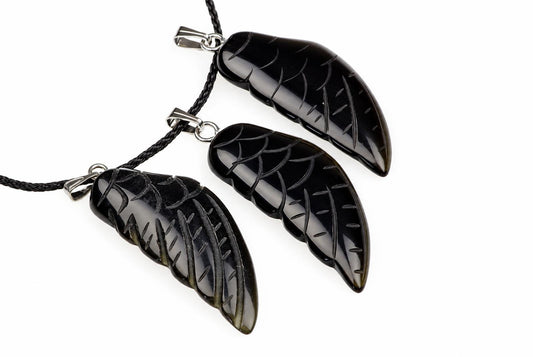 Three black onyx pendants shaped like wings, each with carved vein details and a silver-toned bail on a dark cord against a white background.