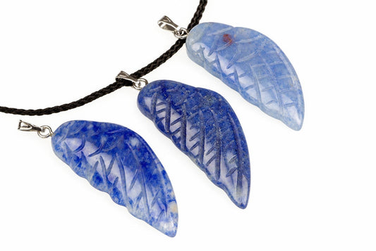 Blue quartz wing pendants with pale patches, carved feather grooves and silver-tone loops are arranged with a dark cord against white.