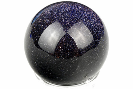 A dark, glittering sphere with a blue upper section and white reflections sits on a clear base against a white background.