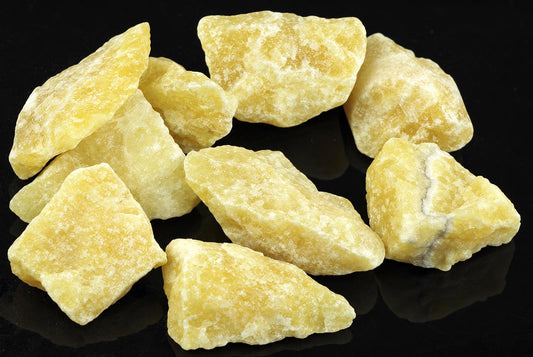 Several yellow calcite pieces with rough, uneven shapes rest on a dark surface.
