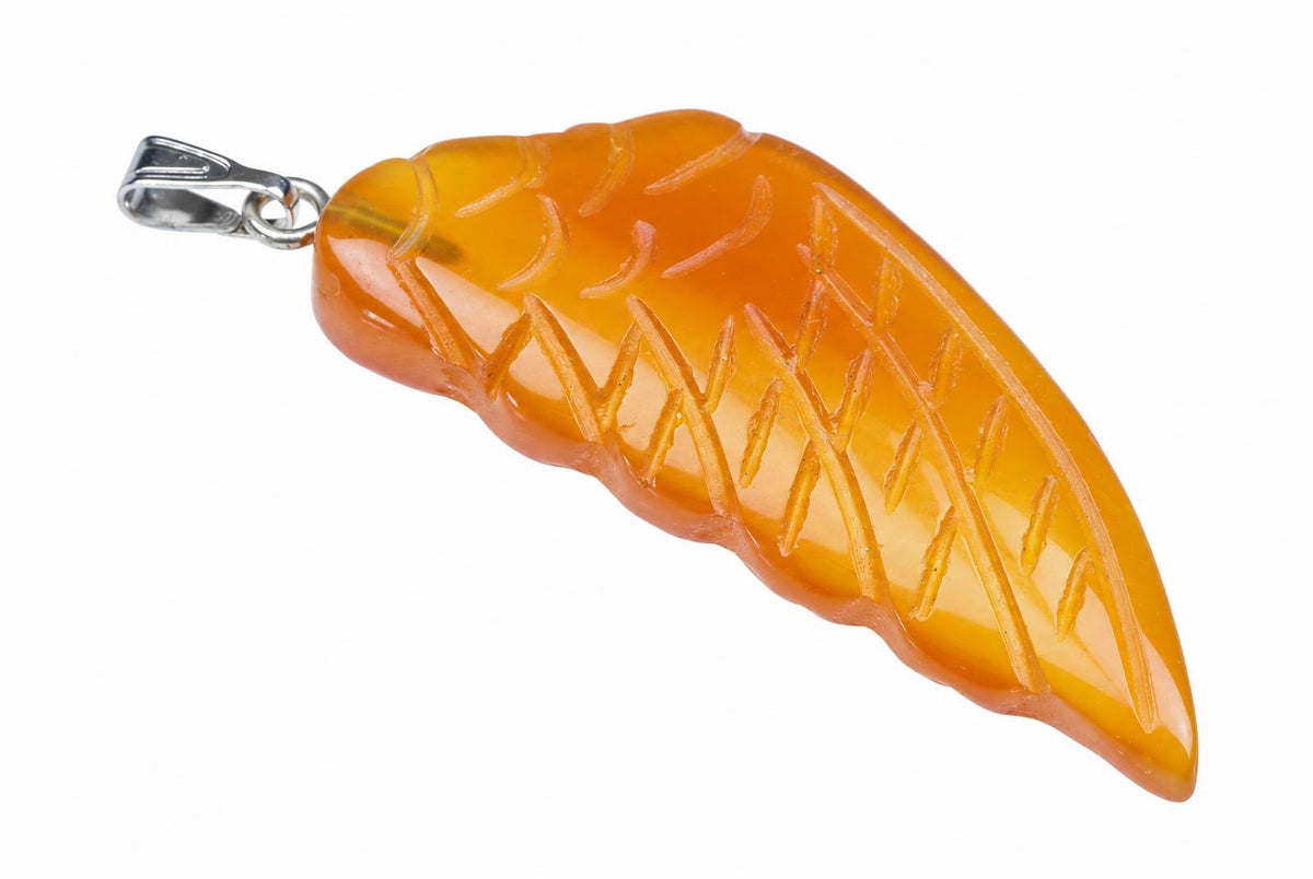 A silver-toned pendant with a carved, translucent orange stone shaped like a wing, set against a white background.