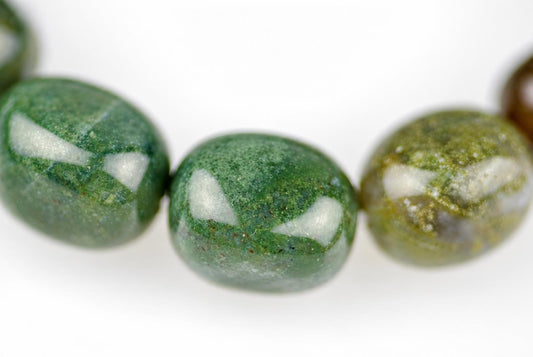 Close-up of polished, rounded green and olive bracelet beads with mottled markings and bright reflections, arranged in a curved row on a white background.
