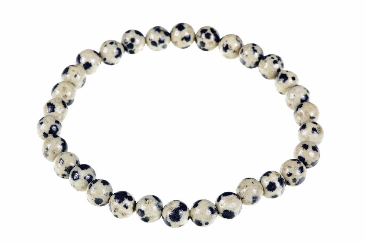 A bracelet made of round beads with a cream background and dark spots, arranged in a circle on a white surface.