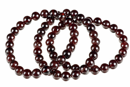 A strand of round, dark red beads with a glossy finish arranged in loops on a white background.