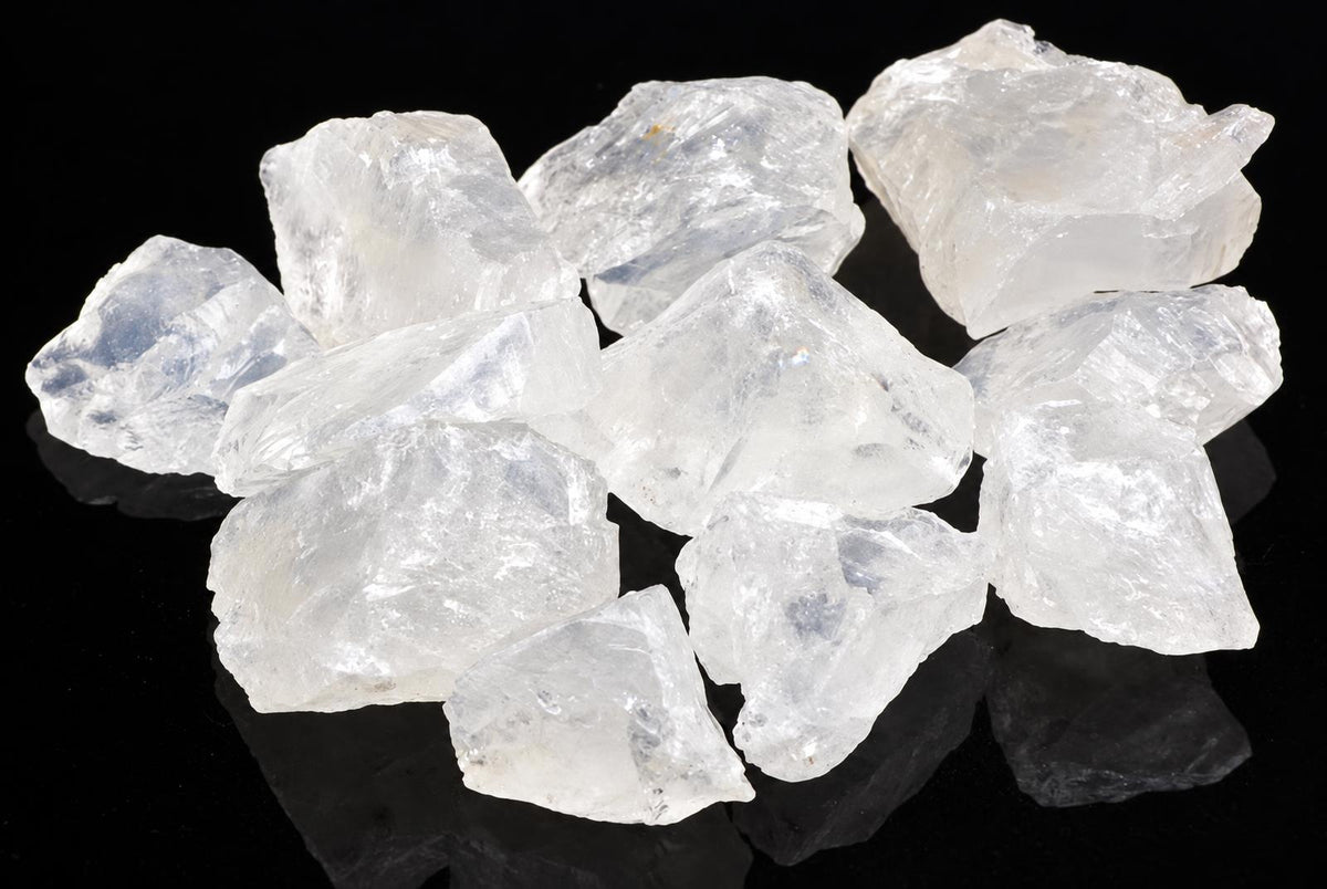 A pile of translucent, white to pale blue crystals with rough shapes on a dark surface.