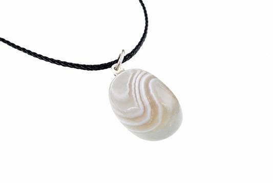 A silver-toned pendant with a smooth, oval grey and white striped stone hangs from a black braided cord against a pale surface.