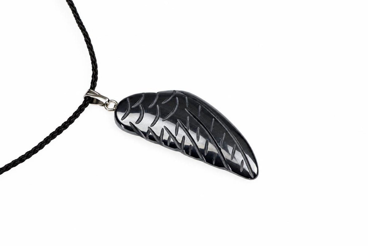 A black wing-shaped pendant with engraved lines hangs from a dark cord on a white background.