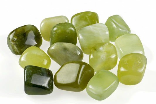 A collection of polished green jade stones in various shades, arranged on a white surface.