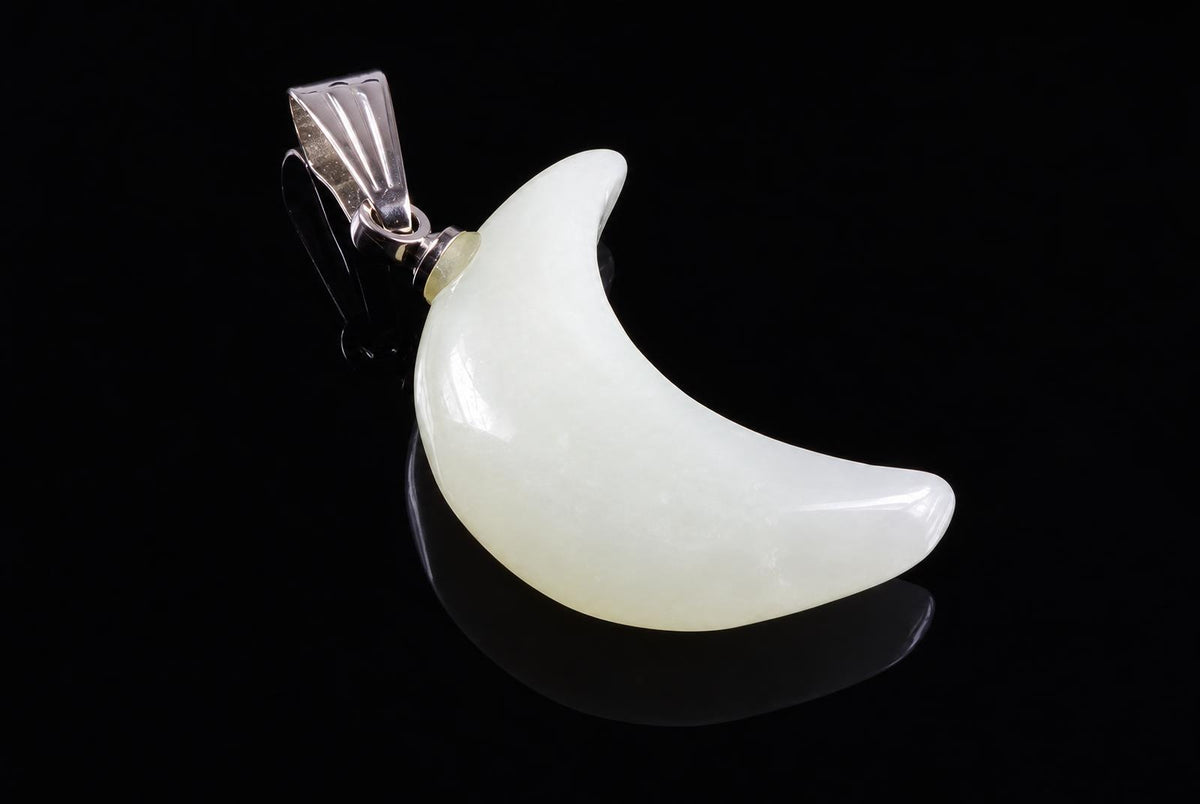 A silver-toned pendant with a pale, crescent-shaped stone on a dark surface.