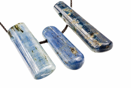 Three polished kyanite pendants with blue and white stripes hang from dark cords against a white background.